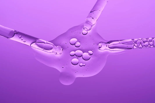 Pipete cu ser cosmetic si picaturi pe fundal mov