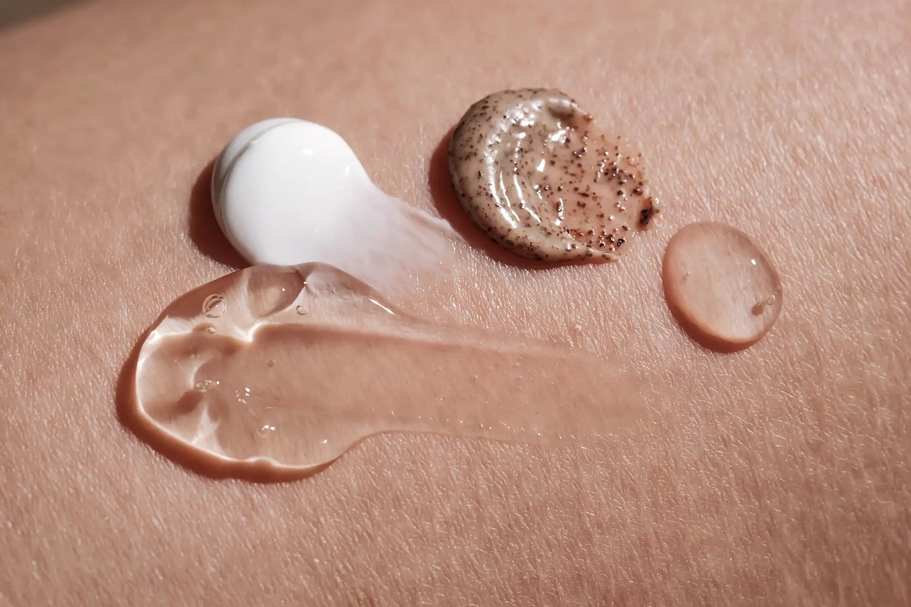 Various skincare product textures swatched on skin including cream serum and scrub