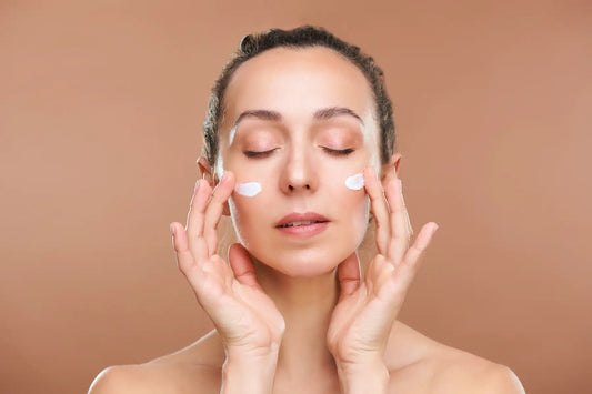 Femeie aplicand crema pe obraji cu ochii inchisi
