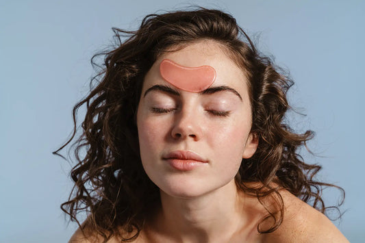 Femeie cu ochii inchisi aplicand un plasture hidrogel pe frunte pentru calmarea si hidratarea pielii